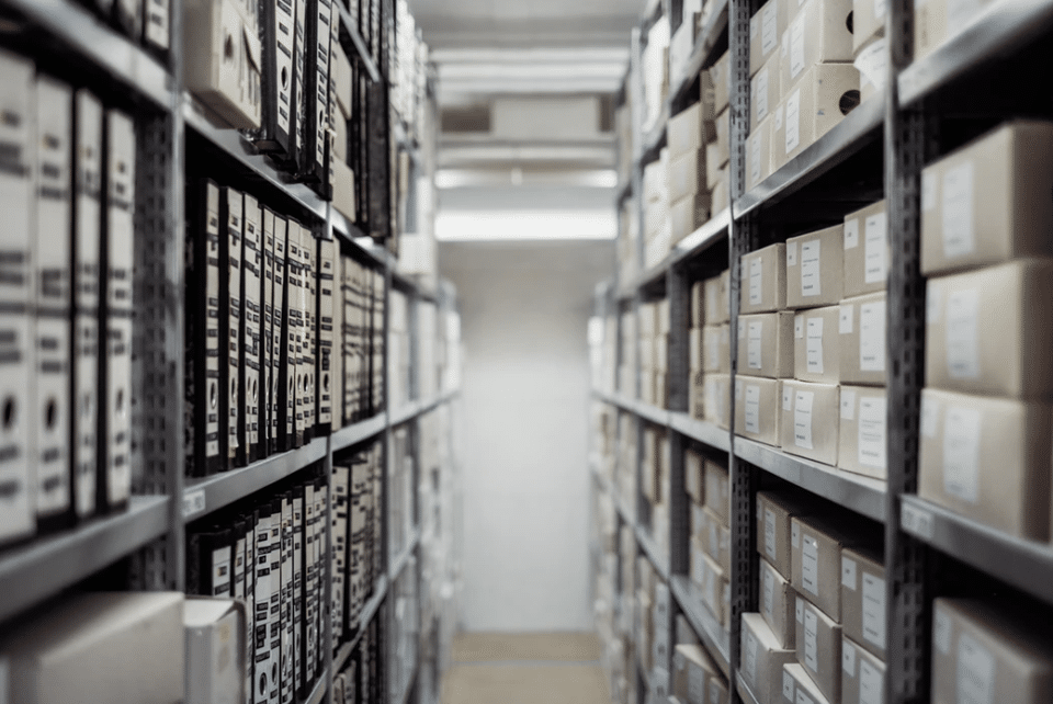 An aisle of a stock room with shelves of boxed inventory