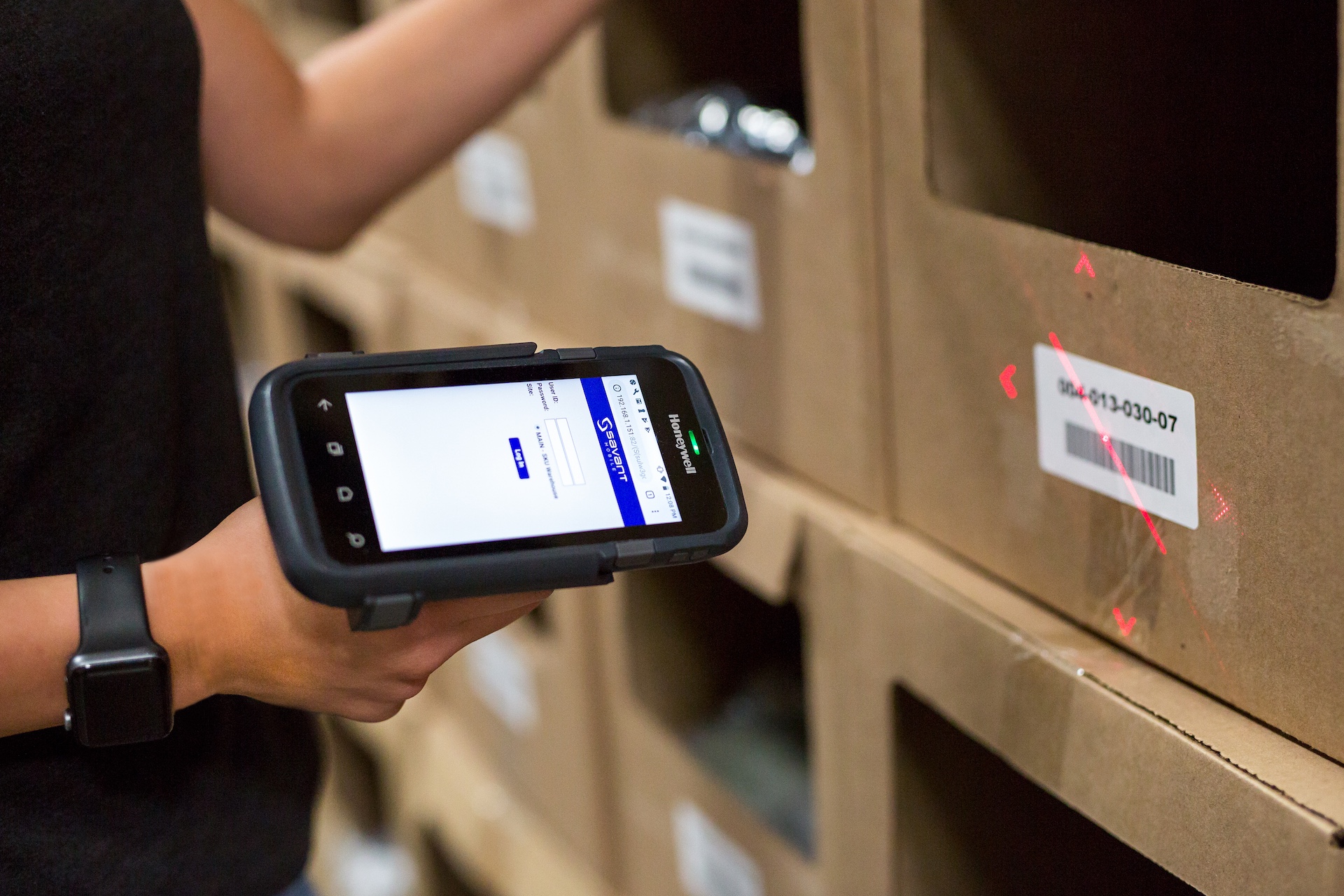 Warehouse worker scanning a barcode label on a carton with a handheld device